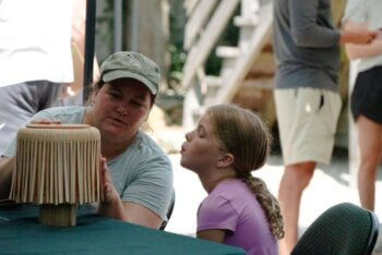 Woman and child weaving a basket.