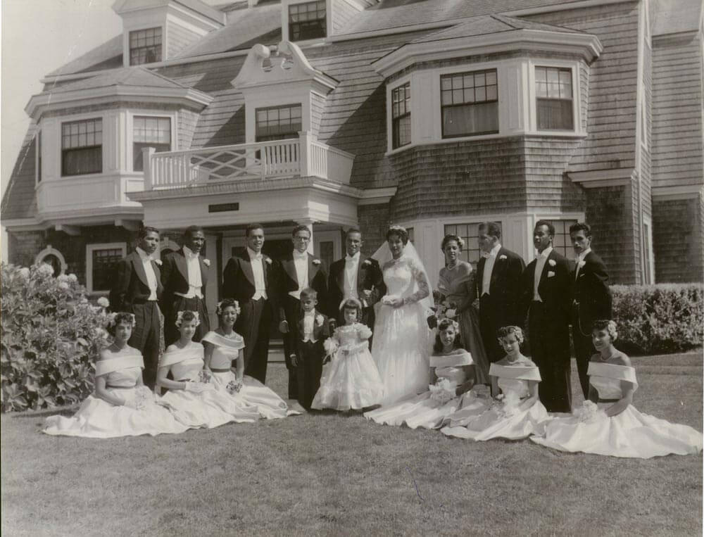 Wedding party in front of a large home.